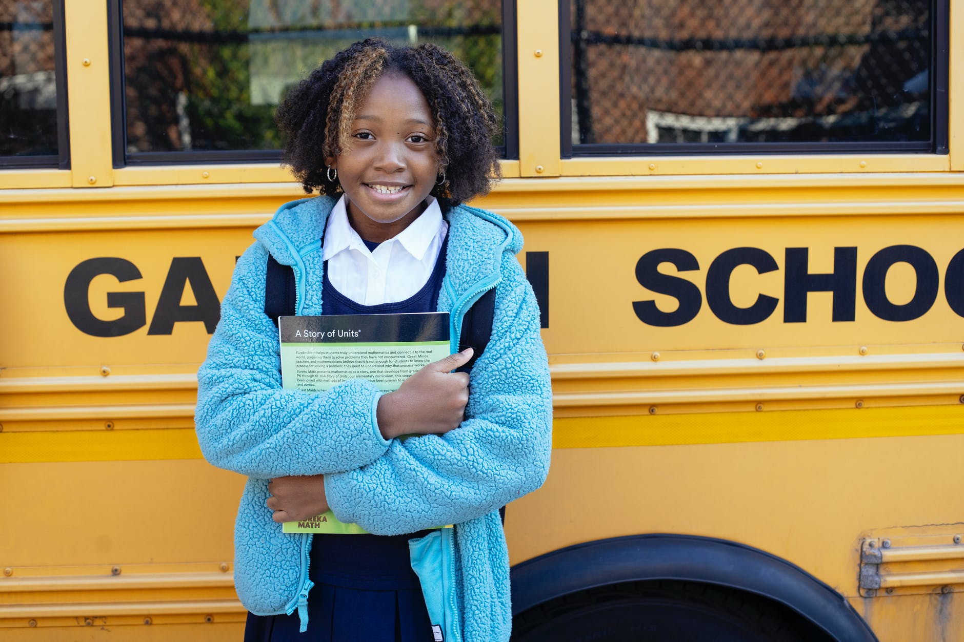 smiling black schoolgirl with textbook